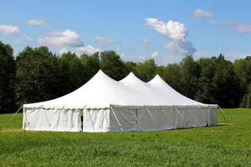 a white wedding or entertainment tent in a green field - 34289650