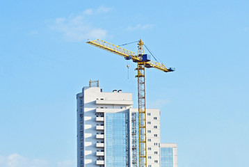 Building crane and building under construction against blue sky