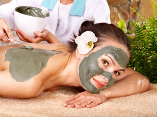 Young woman  having clay body mask.