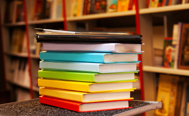 Stack of colorful books with electronic book reader