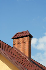 The roof of a modern house with brick chimney