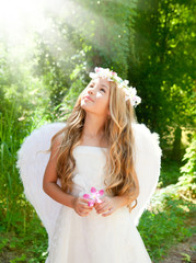 Angel children girl in forest with flower in hand