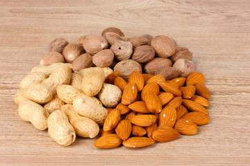 nutmeg, peanuts and almonds on wooden background
