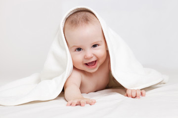 Happy baby under white blanket