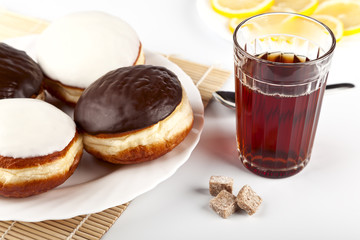 A cup of hot black tea and a plate of donuts
