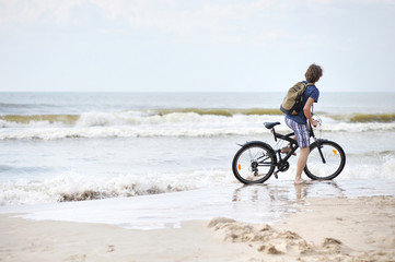 Fototapeta na wymiar Young man bicycling along al beach, Baltic sea