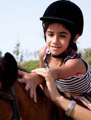 bambina accarezza dorso del cavallo