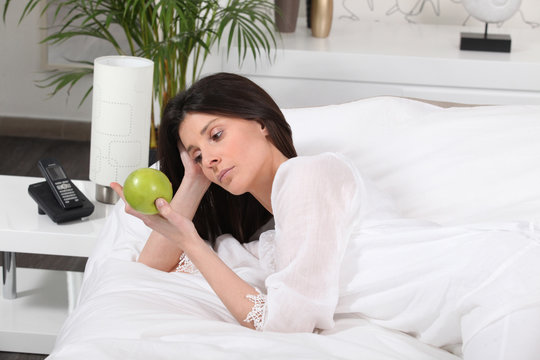 Pensive Woman On Bed Watching An Apple