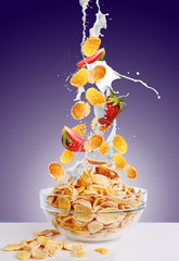 Falling gold corn flakes and strawberry with splash of milk