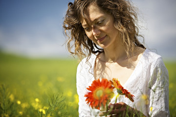 Naklejka premium Woman holding red flowers in field.