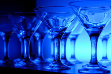Wineglasses arranged in rows on the table in blue light