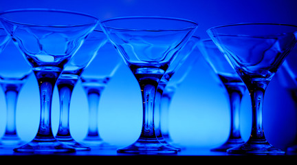 Wineglasses arranged in rows on the table in blue light