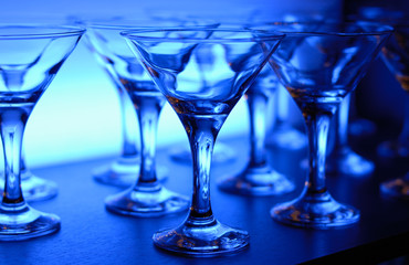 Wineglasses arranged in rows on the table in blue light