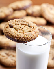 A hand dipping cookies in milk
