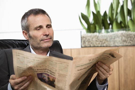 Businessman reading newspaper in office.
