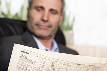 Executive reading newspaper in office.