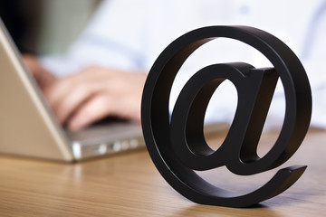 Close up of at symbol with laptop.