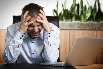 Angry business manager in front of office computer.