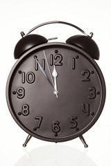 Alarm clock showing five minutes to twelve.