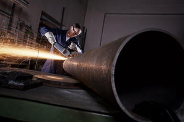 Worker cutting pipe with angel grinder. - obrazy, fototapety, plakaty