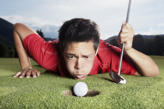 Golfer blowing ball into cup.