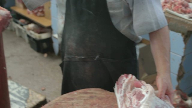 Butcher chopping bones of mutton leg with axe
