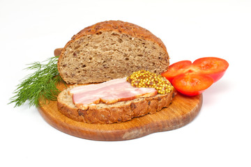 Bread with ham, mustard, dill and tomato on the wood plate