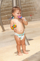 Cute baby girl with two large lollipops at a park
