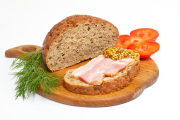 Bread with ham, mustard, dill and tomato on the wood plate