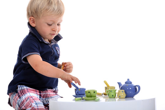 little boy playing with a doll's tea set