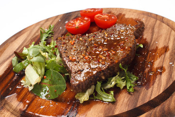Grilled steak with tomato on wooden background