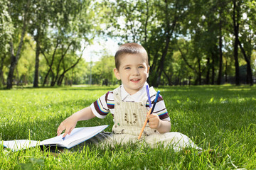 Portrait of a boy with a book in the park