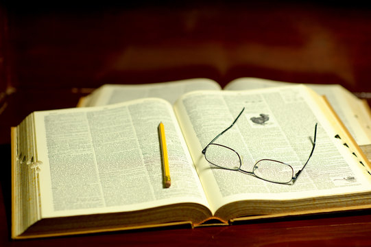 Open book with pencil and glasses