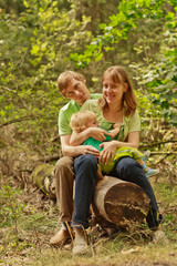 Family outdoors sitting on log smiling