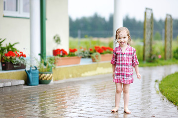 Naklejka premium Little girl having fun under the rain in summer