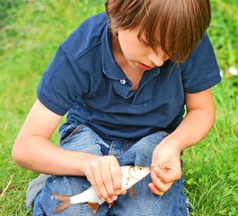 Junge löst Fisch vom Angelhaken