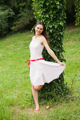 a beautiful young teenage girl posing outdoors in a dress.