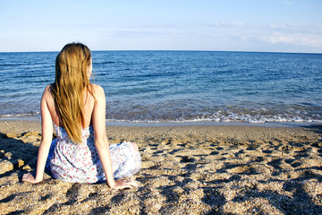 Young lady sitting on the beach near the sea