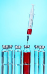 medical ampoules and syringe on blue background