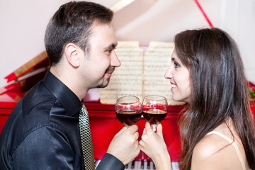 Couple with glasses of wine near piano