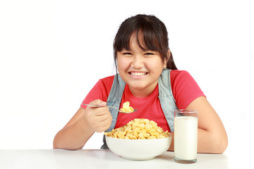 portrait of smiling young girl having breakfast against white