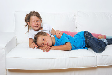 Zwei Kinder liegen auf dem Sofa