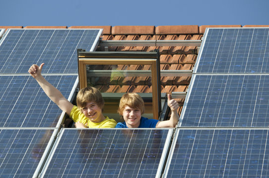 Kinder in Dachfenster mit Solarplatten
