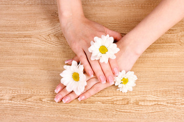 Obraz na płótnie Canvas beautiful woman's hands and flower on wooden background