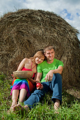 Naklejka na ściany i meble couple with apples sitting on the grass hay