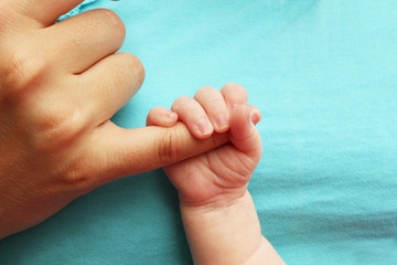 Newborn baby clutching mothers finger