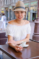 Young pretty woman in street cafe with cup
