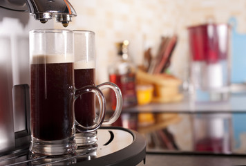 Two coffee shots by espresso machine in kitchen