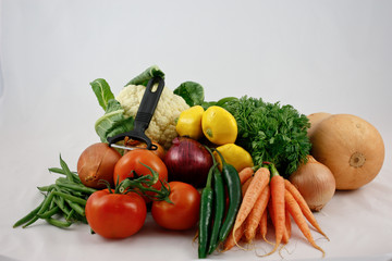 Fresh vegetables with vegetable peeler isolated on white