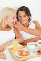 Obraz na płótnie Canvas Portrait of smiling man giving a strawberry to his girlfriend